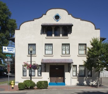 The real Tuality Lodge facade, with its broad Mission Revival parapet, central upper opening, windows, tiled awnings and entrance.